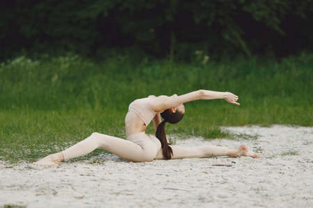 Woman practicing advanced yoga in a beachの写真素材