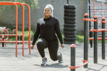 Afro-american plus size woman doing workout exercises session outdoorの写真素材