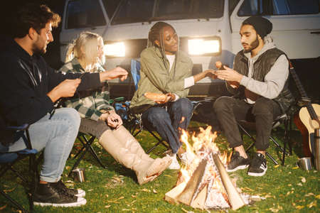 Multi ethnic friends having picnic by fireplaceの写真素材