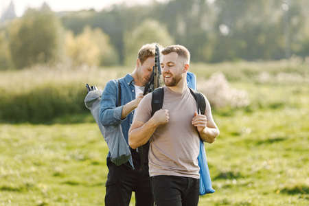 Two men talking and carrying fishing equipment outdoorsの写真素材