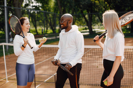 Two women and black race trainer at tennis court