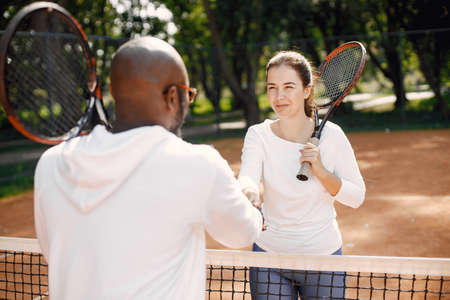 Man and woman handshaking at tennis courtの写真素材