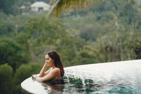 Woman in a swimming pool on a jungle viewの写真素材