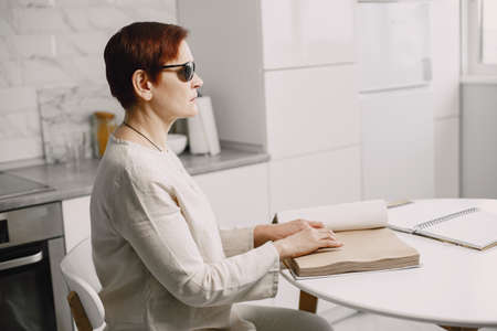 Blind mature woman reading braille book at homeの写真素材