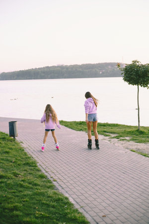 Mother with daughter rollerskating in park with lake