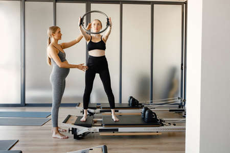 Young pregnant woman with a female coach doing excercises in a gymの写真素材