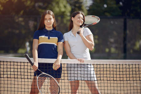 Two female tennis players on a tennis court posing for a photoの写真素材