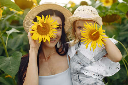 Beautiful woman and child with sunflower in spring fieldの写真素材