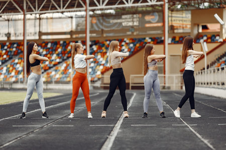 Five sports girls in a uniform training at the stadiumの写真素材