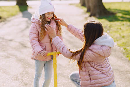 Mother with daughter in a spring park with skateの写真素材