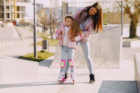 Mother with daughter in a spring park with rollerの写真素材