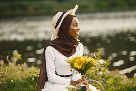 Portrait of a muslim woman sits on the plaid picnic blanket near the riverの写真素材