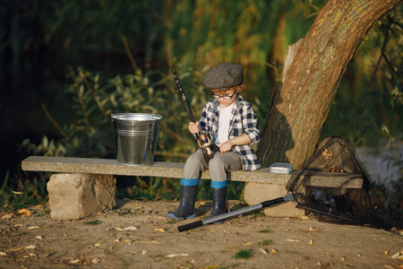 Blonde curly boy sitting on a bench and holding a fishing rod