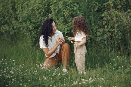 Mother with daughter playing in a summer fieldの写真素材