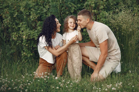 Family with little daughter spending time together in sunny fieldの写真素材