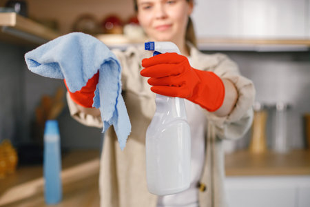 Cropped photo of woman holding a spraying detergent and rug