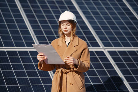 Young woman with checklist standing at solar plantの写真素材