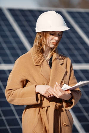 Young woman with checklist standing at solar plantの写真素材