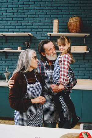 Senior grandparents couple with dgranddaughter cooking in kitchenの写真素材