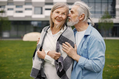 Senior couple standing on a grass in summer and hugging togetherの写真素材