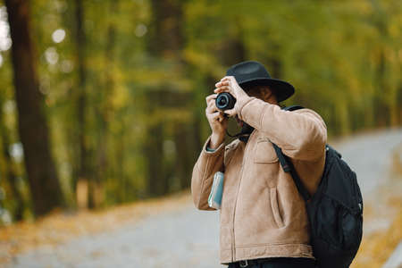 Black man standing on a road and take a photo on a professional cameraの写真素材