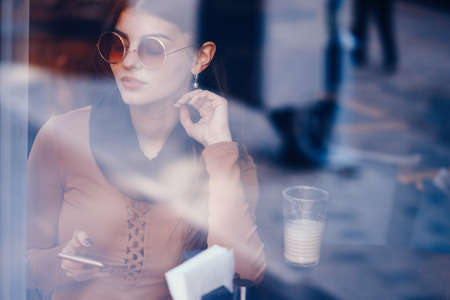 brunette girl using phone while at a restaurantの写真素材
