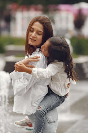 Mom and her little daughter playing by the spray of waterの写真素材