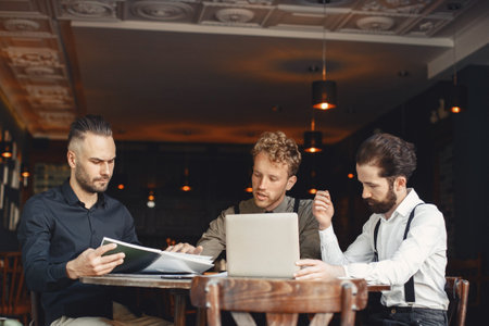 Three men are sitting at a table and talking to each other.の写真素材
