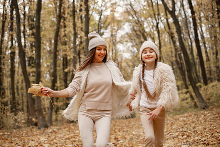 Mother and her daughter playing and having fun in autumn forestの写真素材