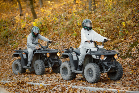 Man and woman driving quad bike in autumn forestの写真素材