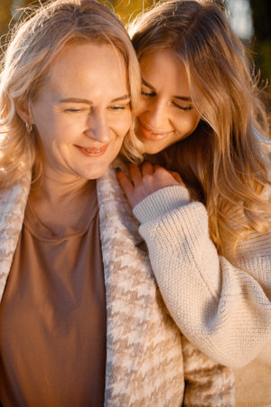 Portrait of mother and daughter hugging at autumn parkの写真素材