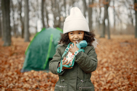 One little black girl holding a flask in hands in the autumn forestの写真素材