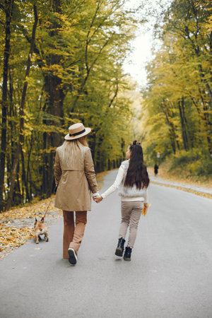 Mother and her daughter with a little puppy french bulldog in a parkの写真素材