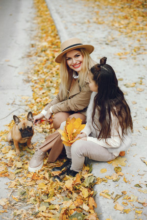 Mother and her daughter with a little puppy french bulldog in a parkの写真素材