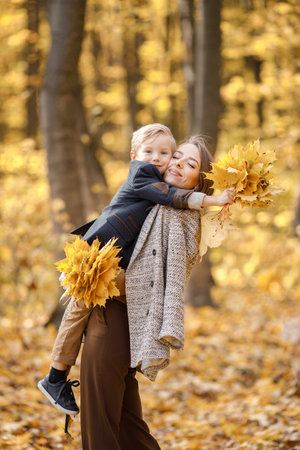 Mother and her son playing and having fun in autumn forestの写真素材