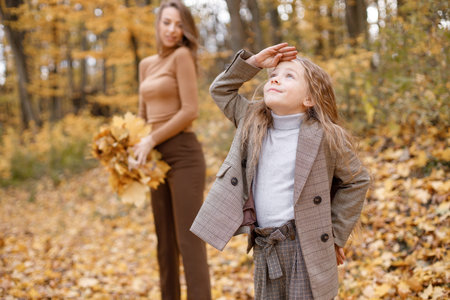 Mother and her daughter playing and having fun in autumn forest