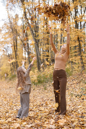 Mother and her daughter playing and having fun in autumn forestの写真素材
