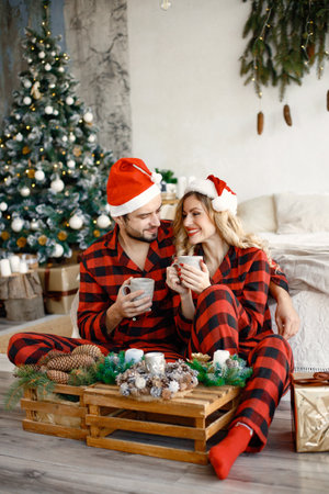 Couple wearing christmas plaid red pajamas sitting on the floorの写真素材
