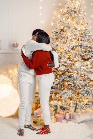 Portrait of happy black couple hugging and standing near Christmas treeの写真素材
