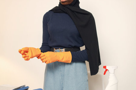 Midsection of arabic woman in cleaning gloves sitting in her office and holding cash