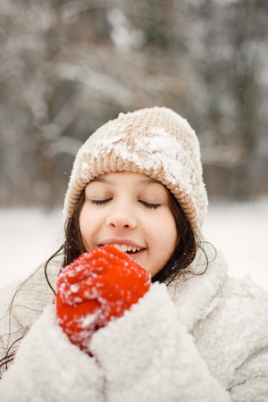Teenager girl in red gloves standing at winter park and posing for a photo