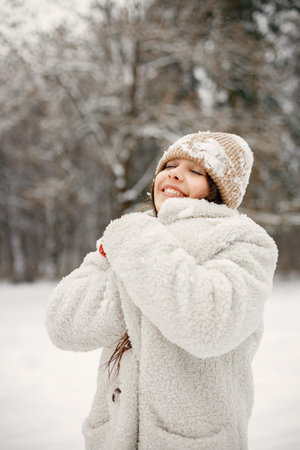 Teenager girl in red gloves standing at winter park and posing for a photo