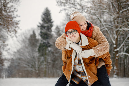 Teen boy and his mother having fun at winter parkの写真素材