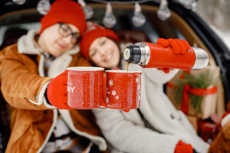 Teen brother and sister sitting in open cars trunk at winter parkの写真素材