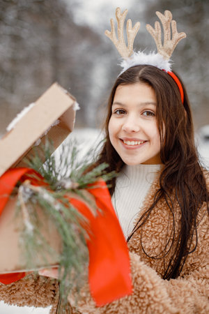 Teenager girl standing at winter park with gift boxの写真素材