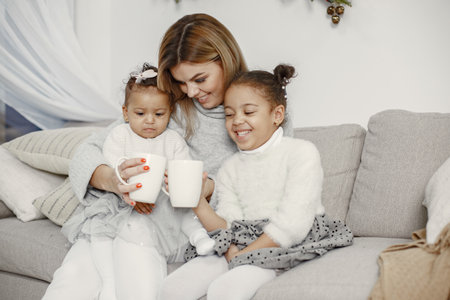 Caucasian mother with two little african daughters at homeの写真素材