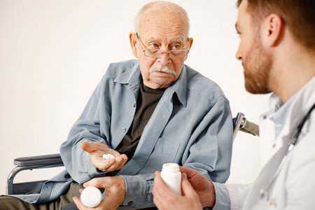 Male doctor and old man on a wheelchair isolated on a white backgroundの写真素材