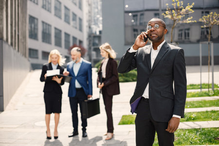 Black businessman standing and talk on the phone in front of modern officeの写真素材