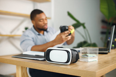 Focus on a virtual reality glasses standing a table of black businessman