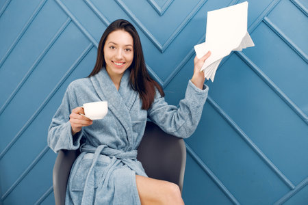 Beautiful girl standing in a studio in a blue bathrobeの写真素材